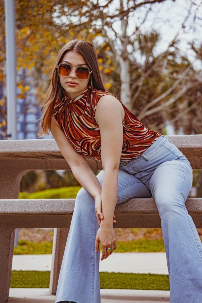 Chic young woman in retro fashion posing on a bench in a Tampa park during autumn.